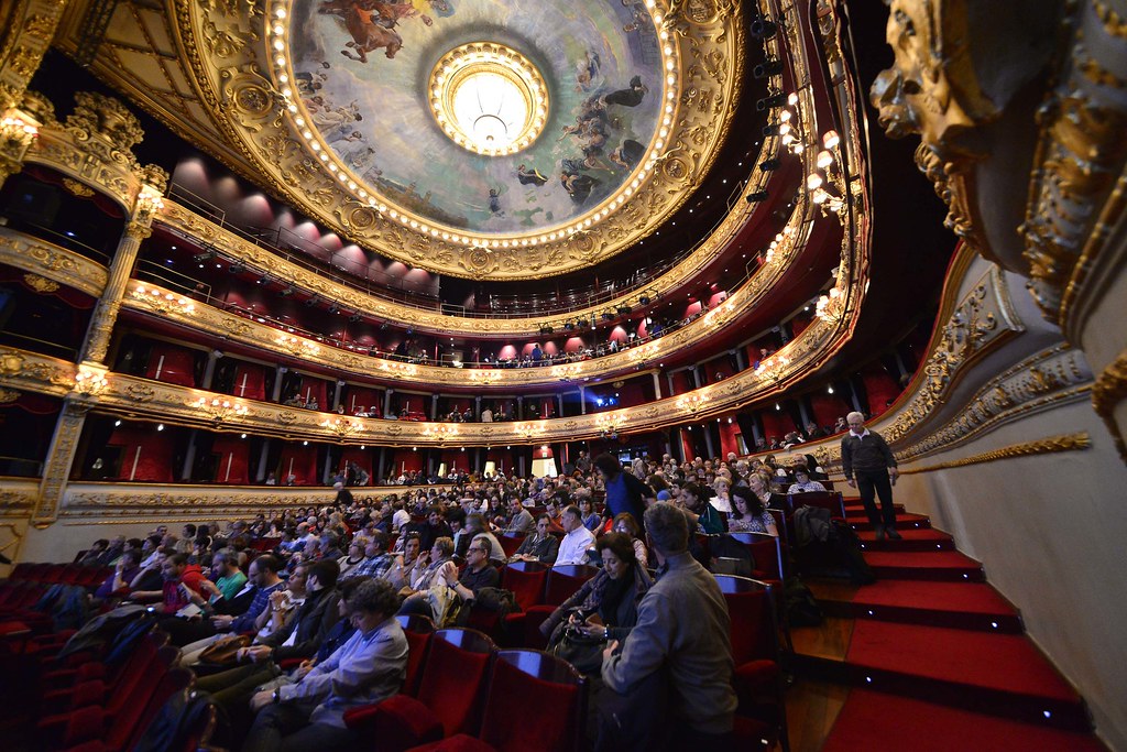 La imagen muestra gente sentada en un teatro.