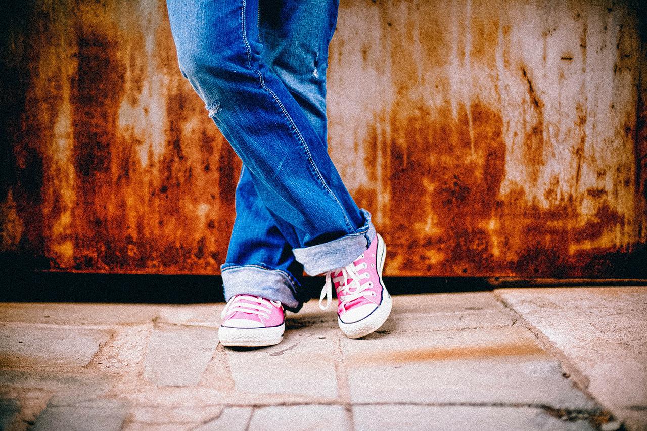 La imagen muestra las piernas de una persona con un pantalón vaquero azul, y unas zapatillas de color Rosa