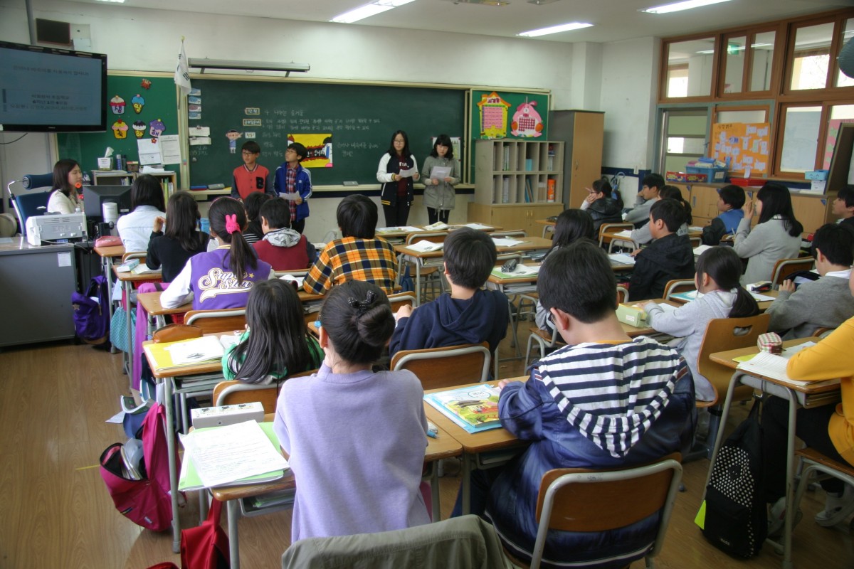 La imagen muestra un aula de un colegio con mesas y sillas