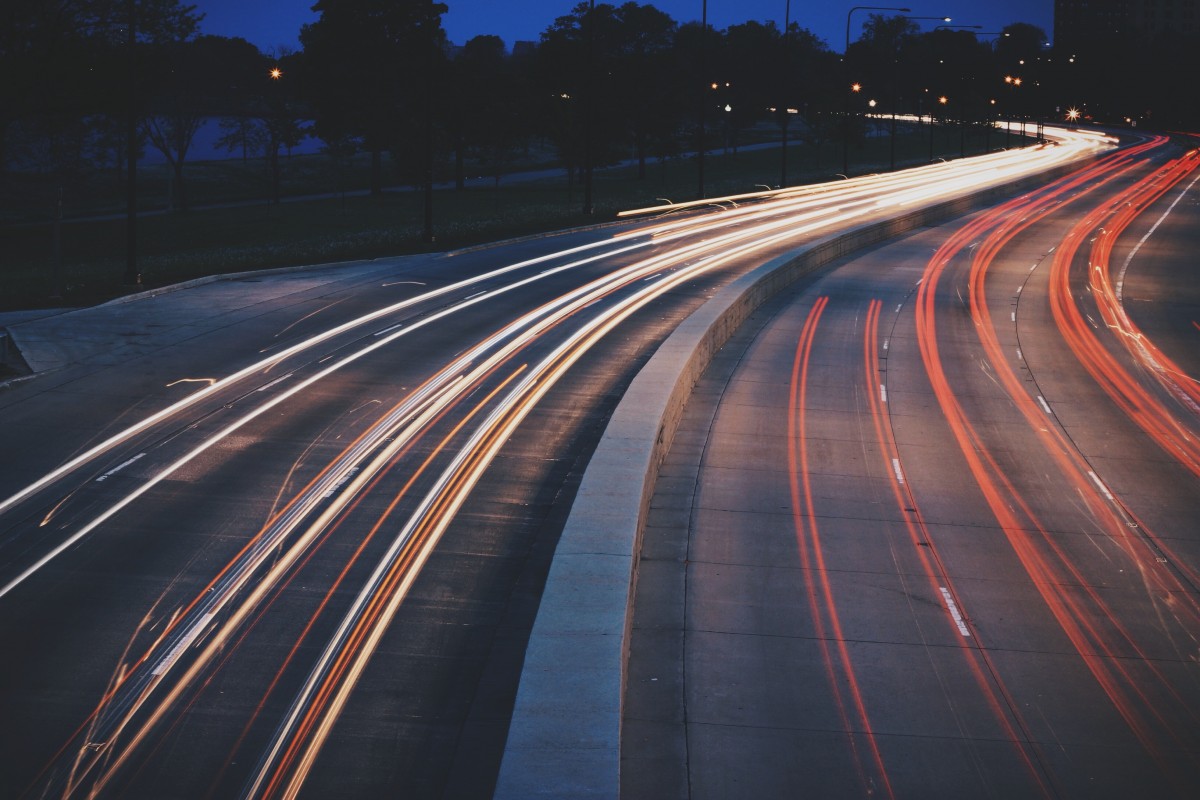 La imagen muestra  una autovía ancha, con luces de coches