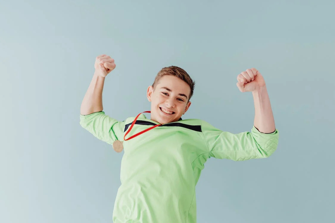 La imagen muestra a un chico con una medalla al cuello porque ha sido el ganador de un juego. 