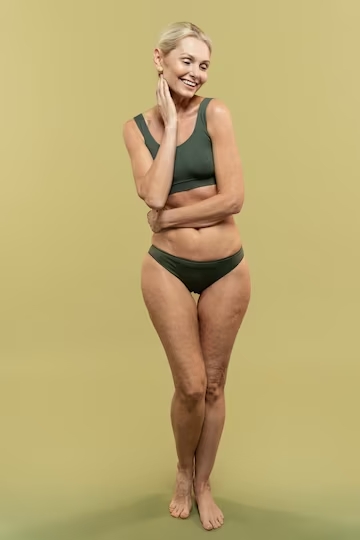 La imagen muestra una mujer rubia con un bañador verde  mostrando su cuerpo.