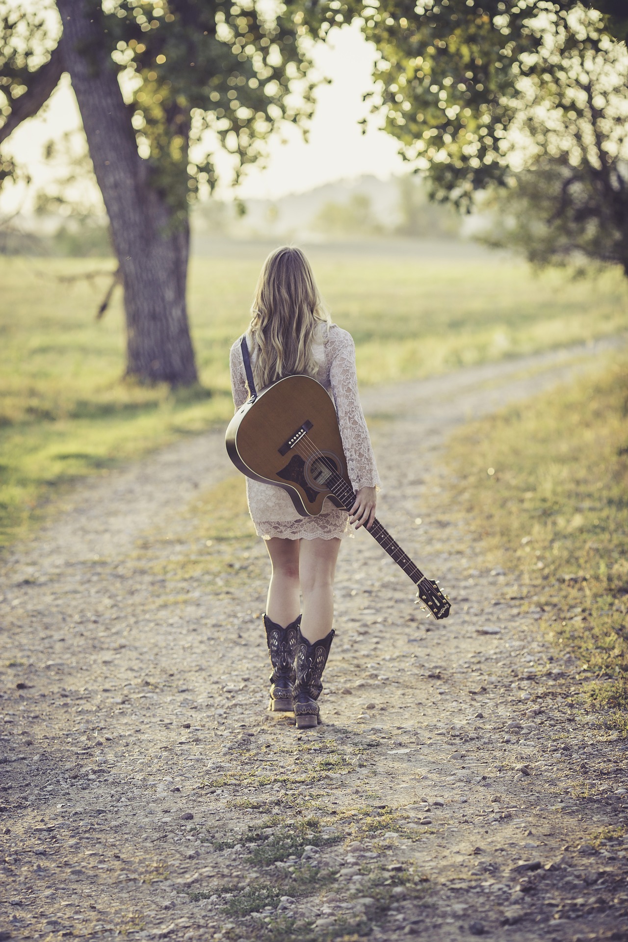 Ana es una chica rubia que camina por el campo con una guitarra.