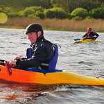 En la imagen se muestra dos personas en una kayak navegando por un lago.