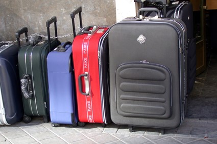 En la imagen se ve una maleta de frente y cuatro maletas más de perfil formando una fila.