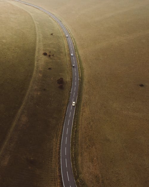 La imagen muestra una carretera asfaltada entre campos de hierba
