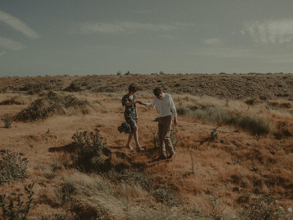 Hombre ayudando a una mujer a caminar sobre la hierba. 