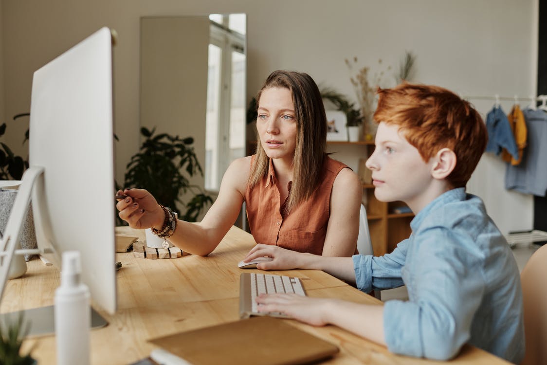La imagen muestra una mujer y un niño mirando atentamente la pantalla de un ordenador.