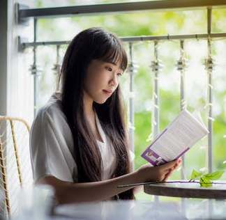 La imagen muestra una chica oriental leyendo un libro sentada.