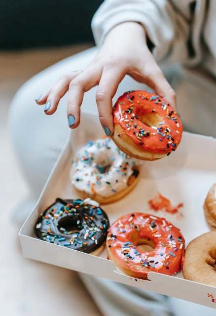 La imagen muestra una mano eligiendo un donuts entre varios.