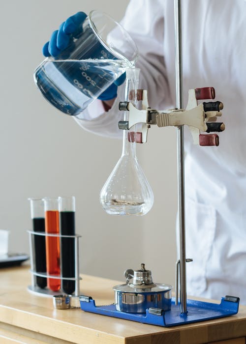 La imagen muestra a un hombre en un laboratorio mezclando líquidos de colores en pipetas.