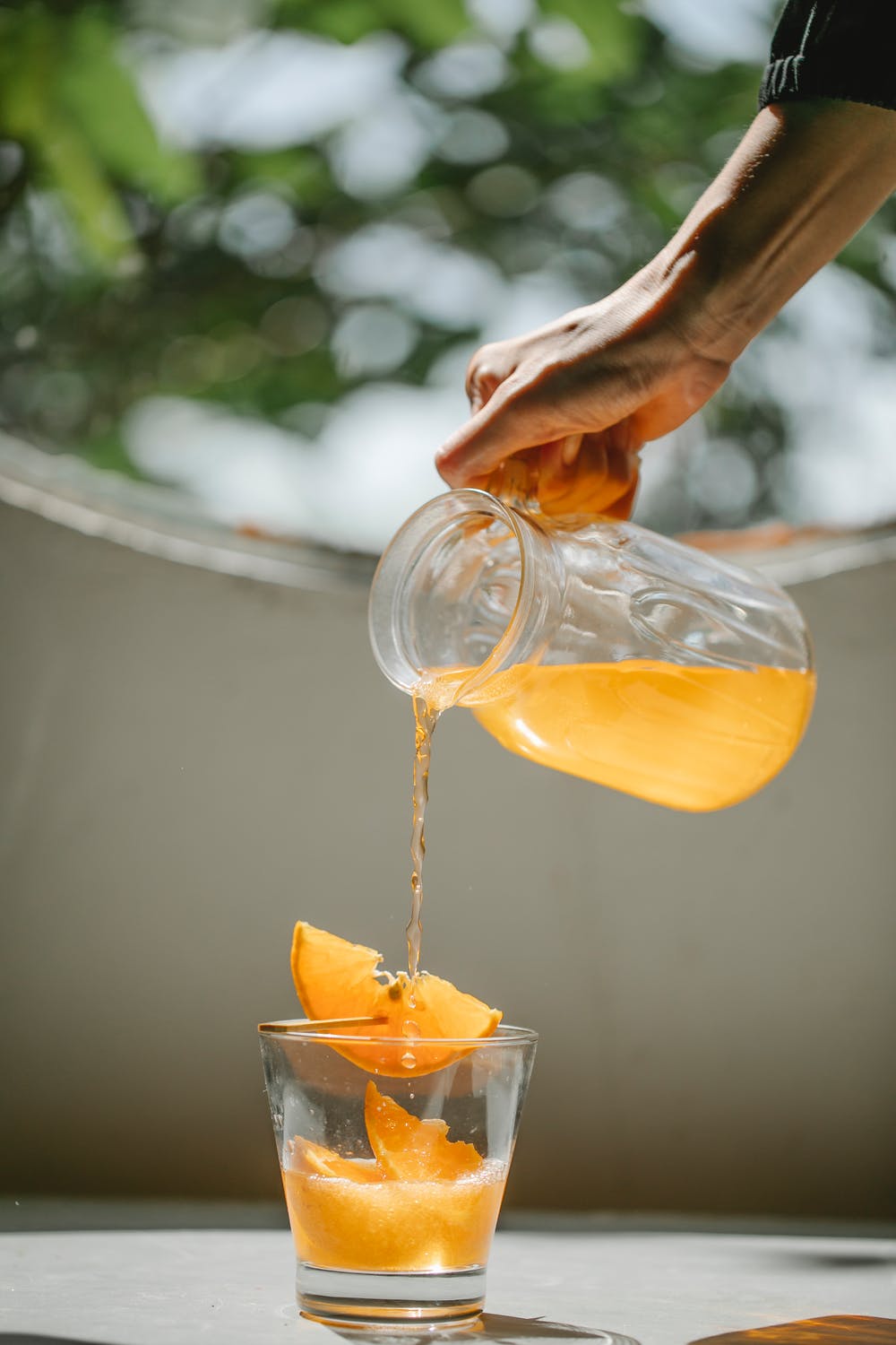 La imagen muestra a una persona echando zumo de naranja en un vaso de cristal. 