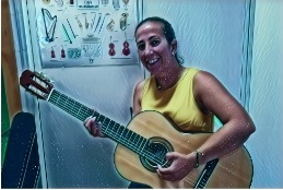 La imagen muestra a una profesora tocando la guitarra