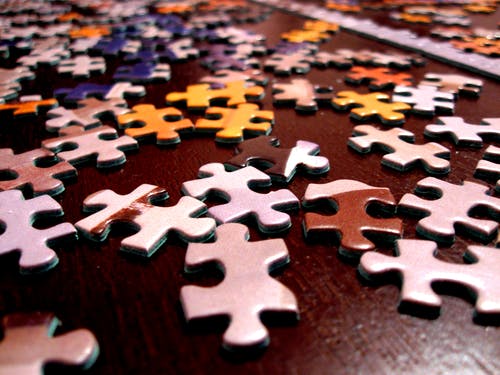 La imagen muestra piezas en varios colores de un rompecabezas sobre una mesa. 