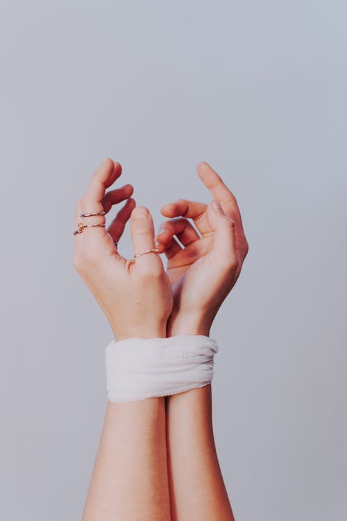 La imagen muestra las dos manos de una mujer atadas juntas  con unas bandas blancas. 