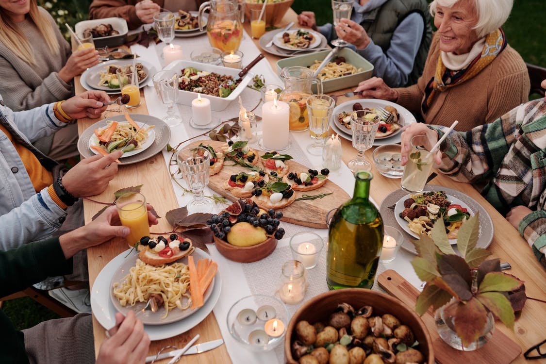 La imagen muestra una reunión familiar en una mesa donde comparten comida. 