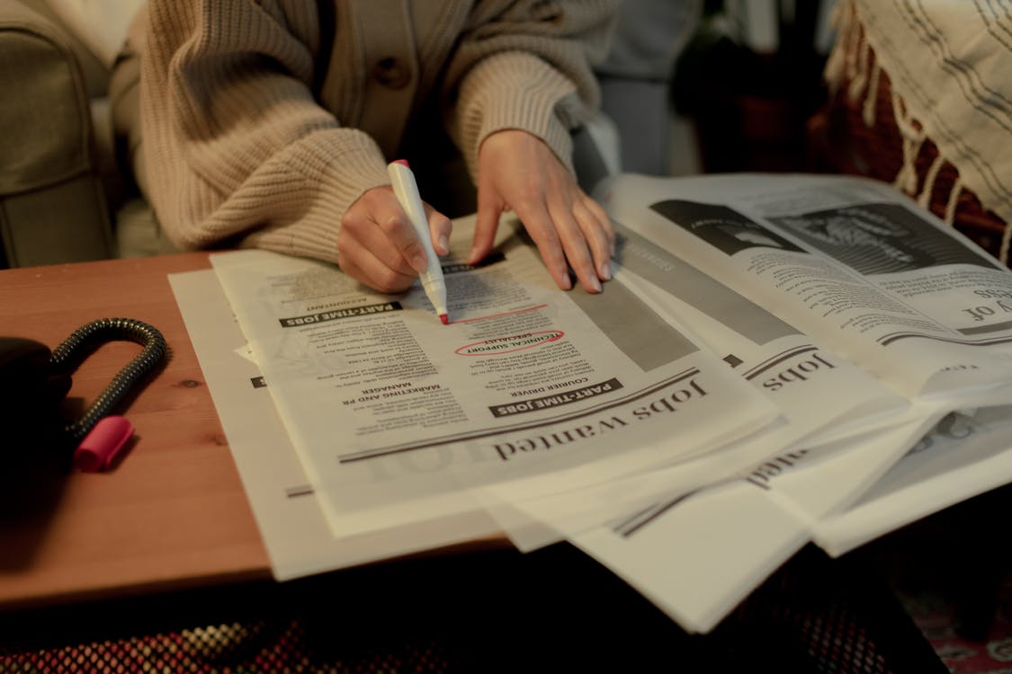La imagen muestra unas manos subrayando un periódico con un rotulador de color rosa.
