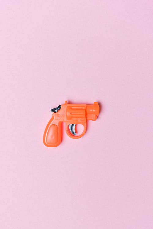 La imagen muestra un revolver de juguete de color naranja.