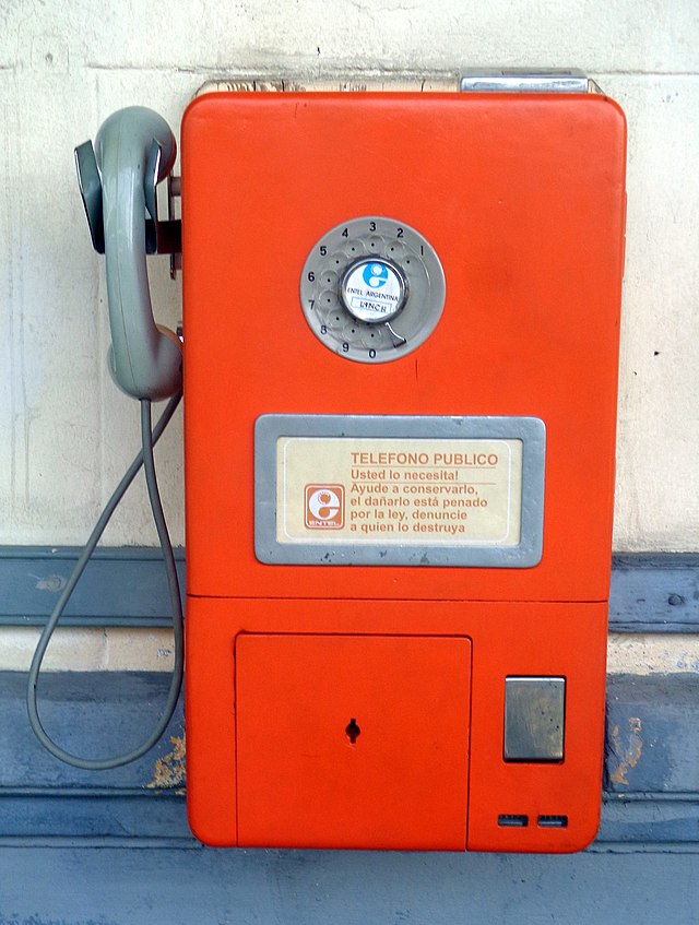 La imagen muestra un teléfono de pared siglo XX.