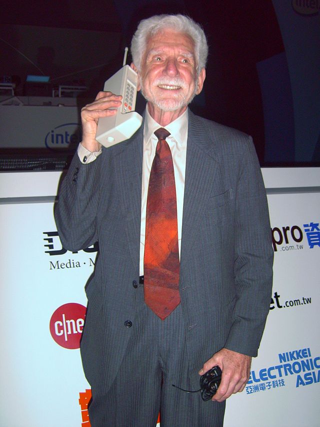  La imagen muestra a Martin Cooper, inventor del primer teléfono móvil, con su invento. 