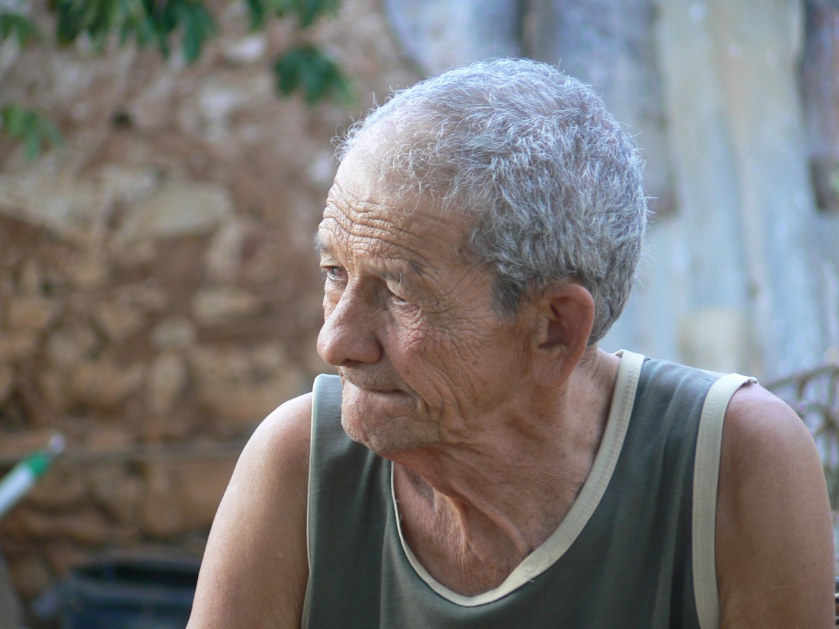 La imagen muestra a un anciano con semblante serio y la mirada perdida hacia un lado.