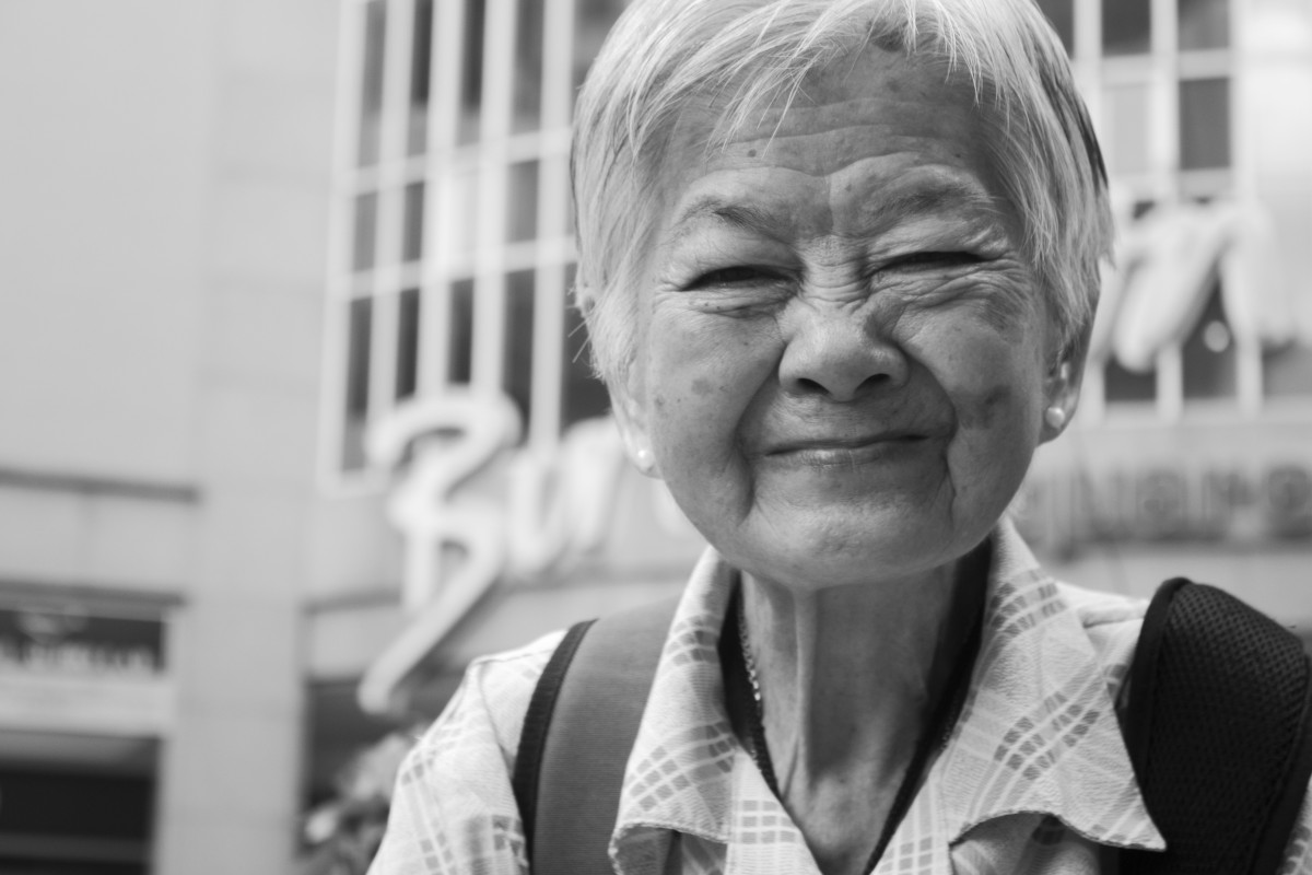 La imagen muestra a una anciana de origen asiático sonriendo.