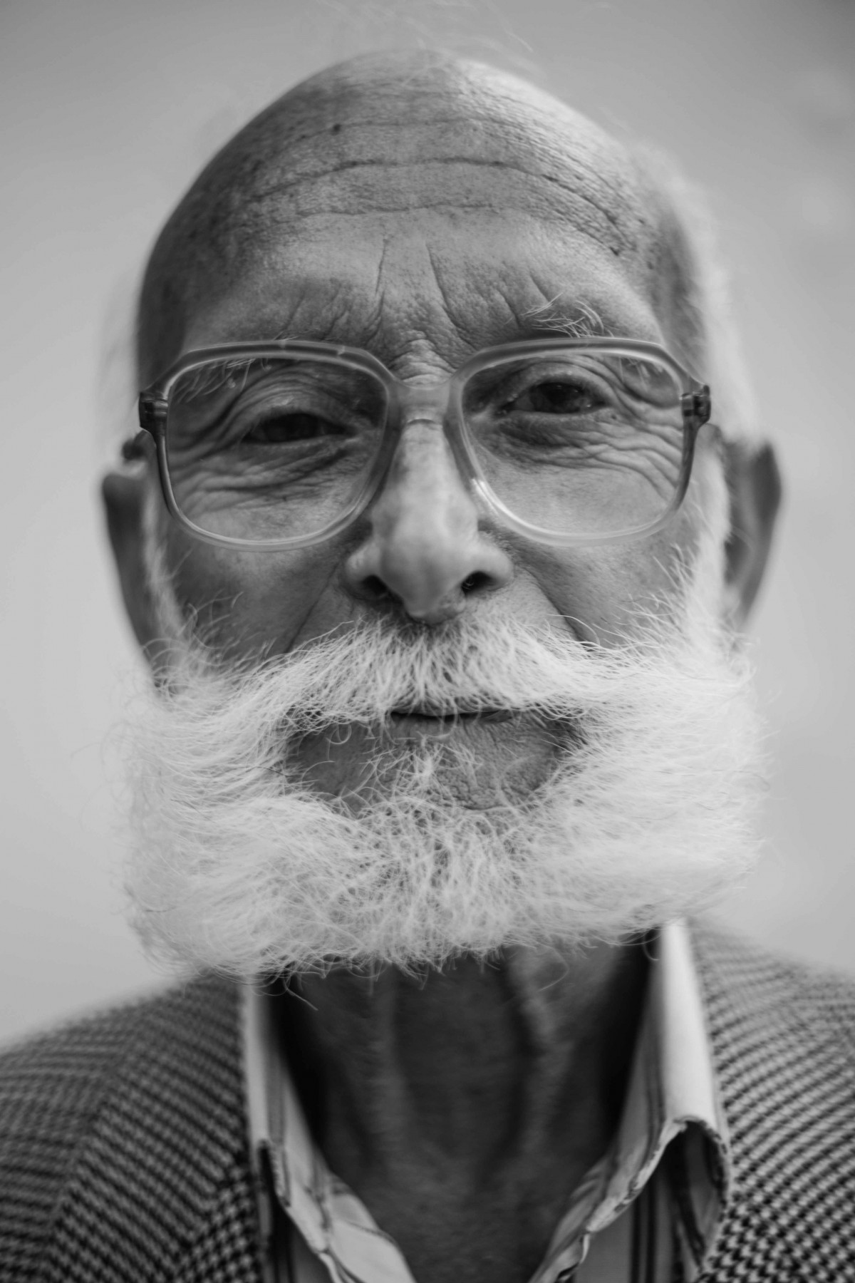 La imagen muestra a un hombre mayor con grandes gafas y una barba larga de color blanco. 