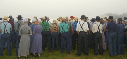 La imagen muestra un numeroso grupo de personas Amish de espaldas.