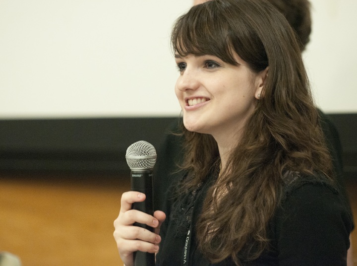 La imagen muestra una joven con un micrófono en la mano en actitud de diálogo.