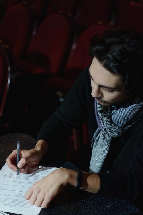 Esta imagen muestra a un hombre haciendo anotaciones en un texto con un bolígrafo.