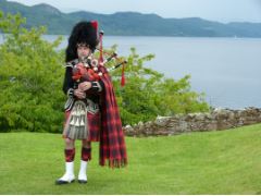 esta imagen muestra a un hombre vestido de escocés y detrás un paisaje