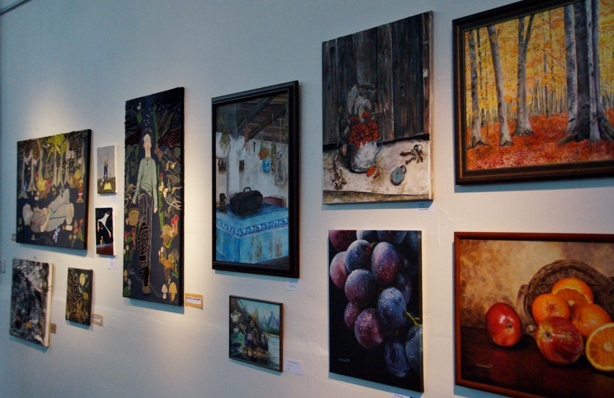 Multitud de cuadros de diferentes tamaños colgados en una pared en una galería de arte