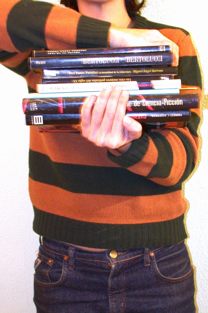 Una pila de libros sostenidos con dificultad por una chica