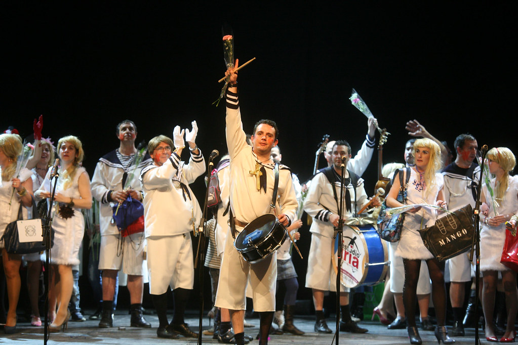 Esta imagen muestra a un grupo de hombres y mujeres con un disfraz de marinero con instrumentos musicales