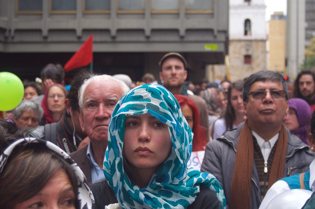 Esta imagen muestra a un grupo de personas de distintas edades y distintas culturas. Una mujer con un pañuelo en la cabeza.