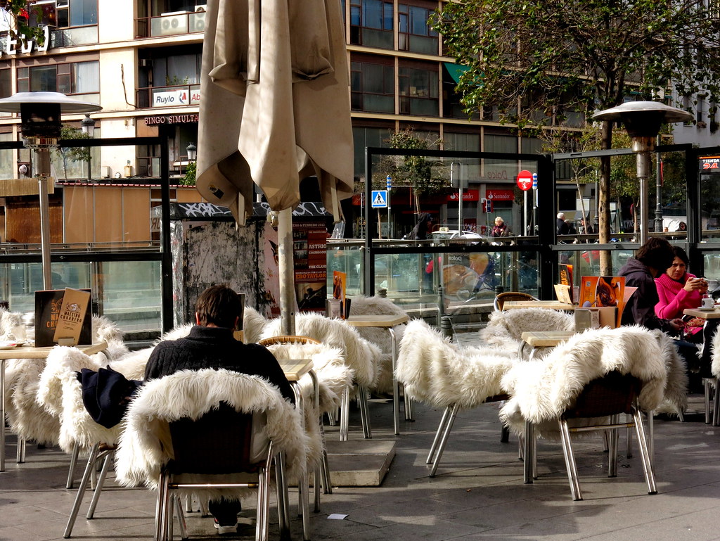Esta imagen muestra una terraza de un bar y en las sillas hay puestas pieles blancas.