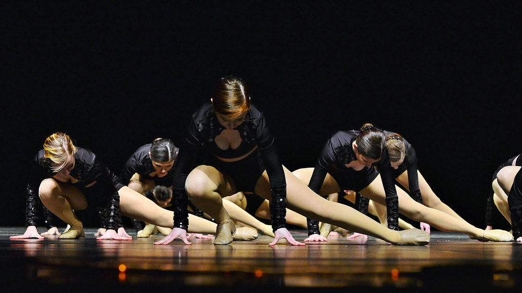 Esta imagen muestra  unas bailarinas con las manos apoyadas en el suelo, una pierna estirada y la otra encogida.